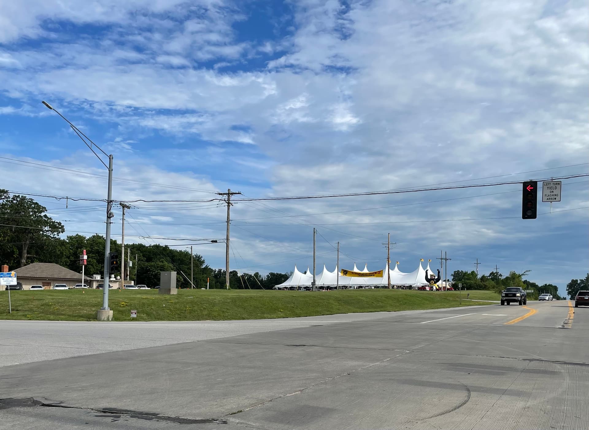Crazy Joe's Fireworks stand seen from the intersection of 171st & Holmes in Kansas City — the long row of white event tents with the yellow Crazy Joe's banner stretches across a green field, easily visible from the road